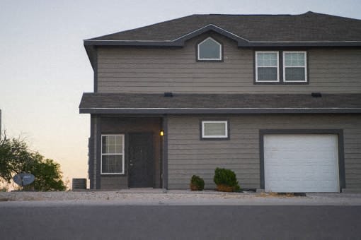 A house with a grey siding and a black door is shown.