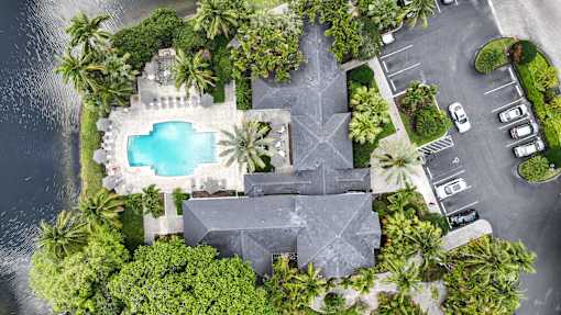 An aerial view of a house with a pool surrounded by trees.