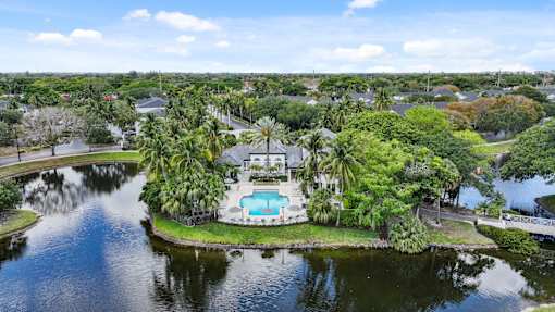 A house with a pool is surrounded by water and trees.