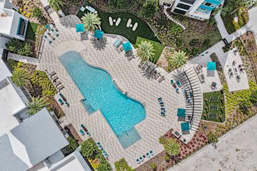 A pool surrounded by a patio and a garden.