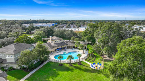 an aerial view of a swimming pool and a mansion with trees and a pool party