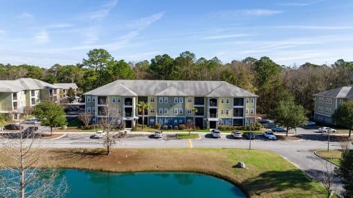 A large apartment complex with a pond in front.