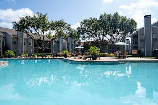 A large swimming pool in front of apartment buildings.