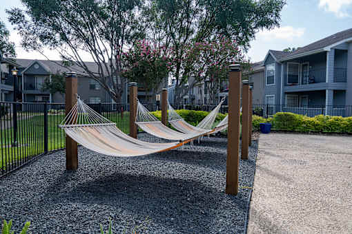 A hammock is strung between two wooden posts in a gravel area.