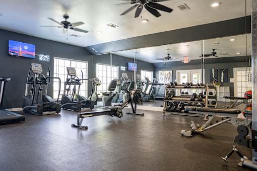 A gym with a variety of equipment including treadmills, weights, and exercise machines.