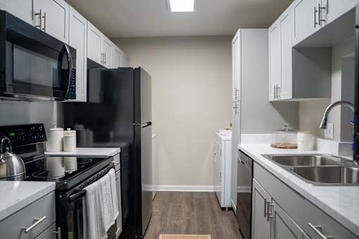A kitchen with black appliances and white cabinets.