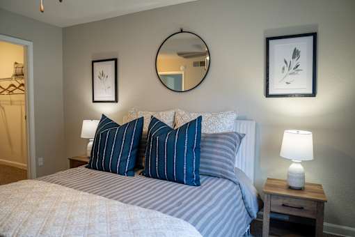 A bedroom with a bed, two lamps, and two framed pictures on the wall.