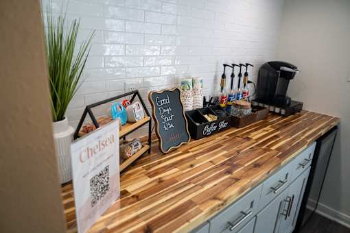A wooden countertop with a sign that says Chelsea and a coffee maker on it.