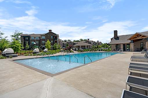 A large swimming pool with lounge chairs and apartment buildings in the background.