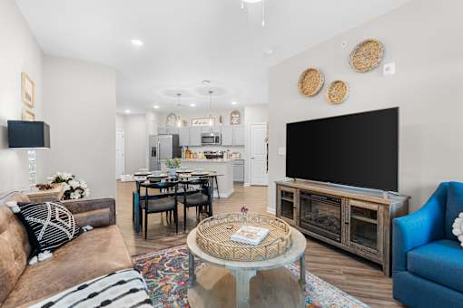 A living room with a brown couch, a glass coffee table, and a black television.