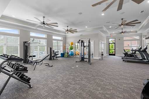A spacious gym with various exercise equipment and a ceiling fan.