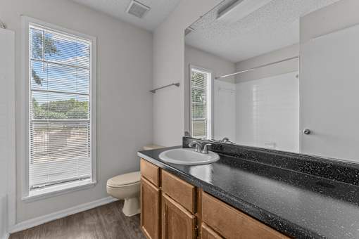 A bathroom with a toilet, sink, and mirror.