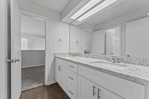 A bathroom with a marble countertop and white cabinets.