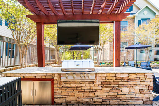 an outdoor entertaining area with a grill and a television