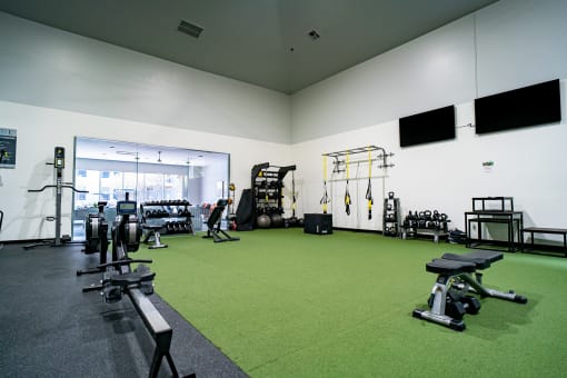 a gym with weights and other exercise equipment on a green carpet