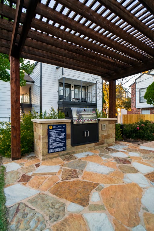 a stone patio with a barbecue grill in front of a house
