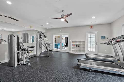 A spacious gym with a variety of equipment including treadmills, weights, and a bench press.