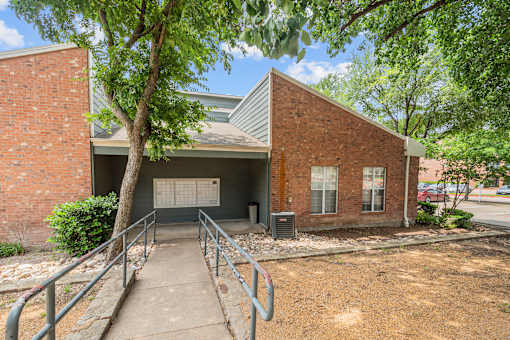 A brick building with a metal roof and a tree in front.