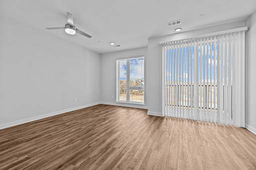A room with a ceiling fan and a window with blinds.