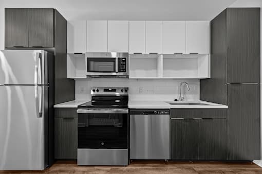 A modern kitchen with a refrigerator, oven, microwave, and sink.