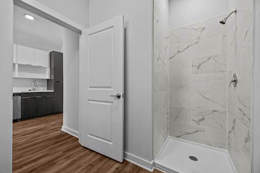 A white door is in a bathroom with marble tiles.