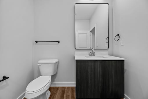A bathroom with a toilet, sink, and mirror.