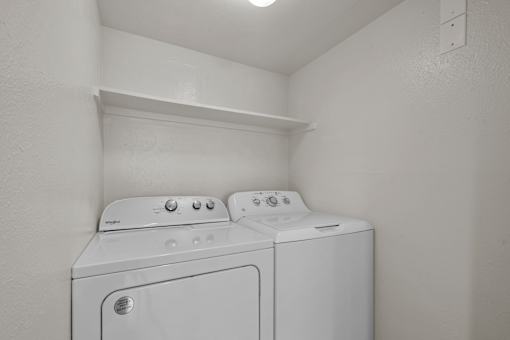 Two white washing machines in a small laundry room.