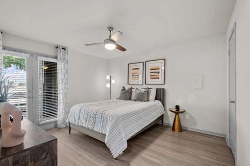 A bedroom with a bed, a ceiling fan, and a window with blinds.
