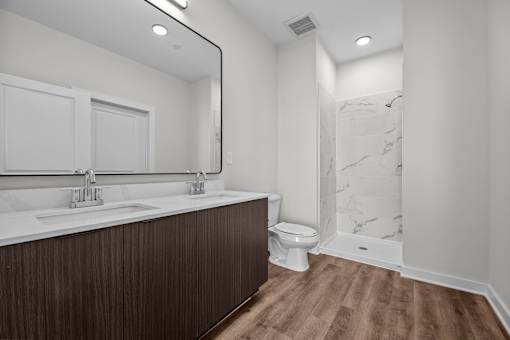 A bathroom with a wooden vanity and a marble shower.