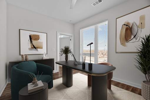 A living room with a blue armchair, a black table, and a painting on the wall.
