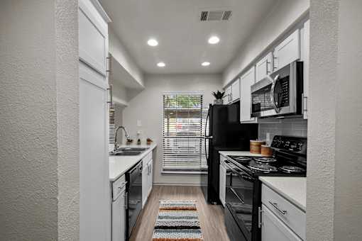 A modern kitchen with black appliances and white cabinets.