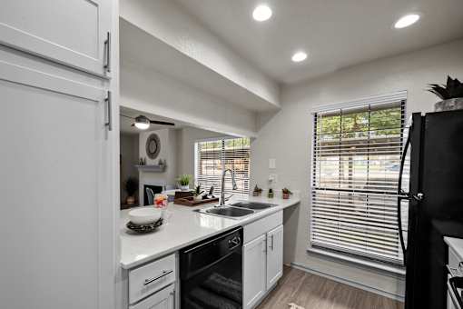 A modern kitchen with white cabinets and a black refrigerator.