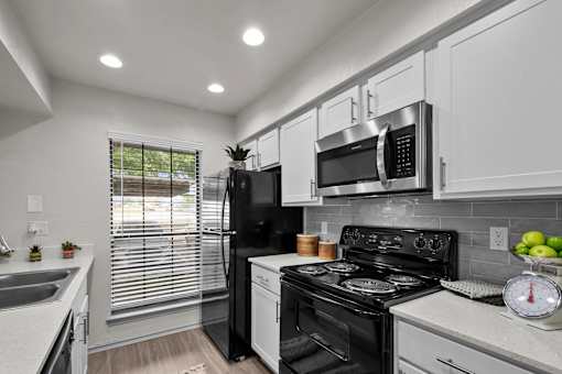 A modern kitchen with a black refrigerator, stove, and microwave.