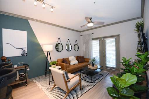 A living room with a brown couch, a black floor lamp, and a painting on the wall.