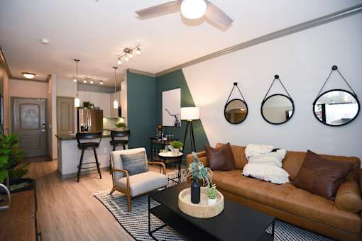 A living room with a brown couch, a white chair, and a black coffee table.