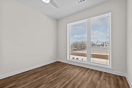 A room with a window covered by white blinds.