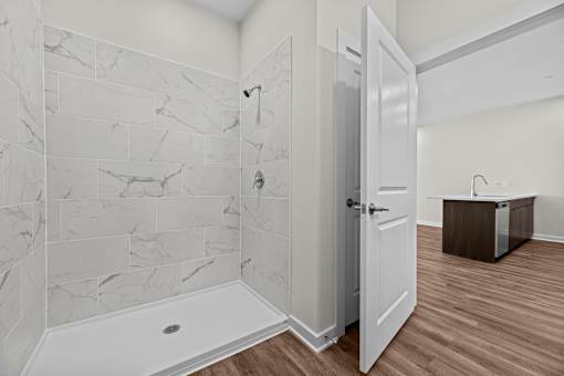 A bathroom with a marble tile shower and a white bathtub.