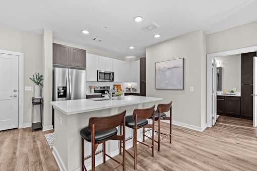 A kitchen with a white counter top and wooden bar stools.