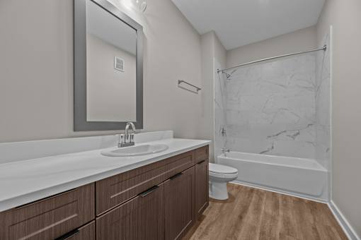 A bathroom with a marble shower and wooden cabinets.