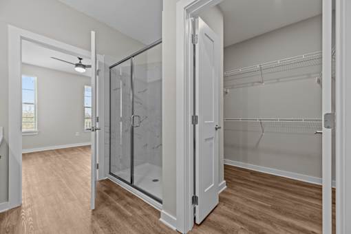 A walk-in closet with a glass door and wooden floors.