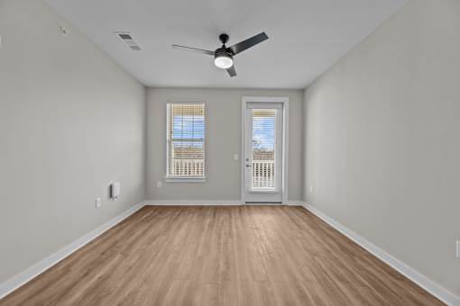 A room with a ceiling fan and wooden flooring.
