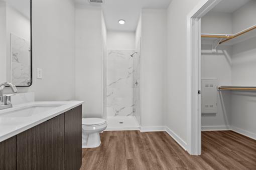 A bathroom with a toilet, sink, and marble wall.