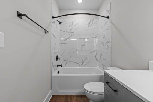 A white bathroom with a marble shower.