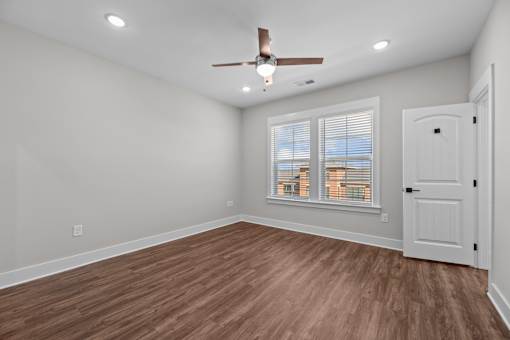 A room with a ceiling fan and wooden flooring.
