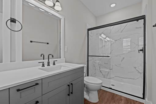 A bathroom with a marble shower and a white sink.