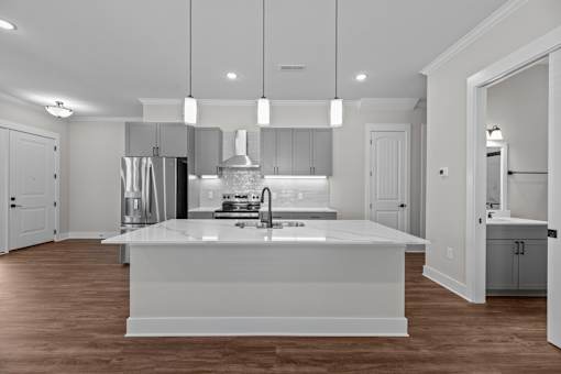 A modern kitchen with a large island and pendant lights.