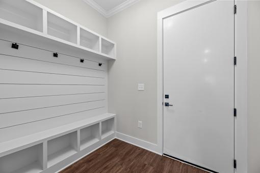 A white closet with a door and shelves.