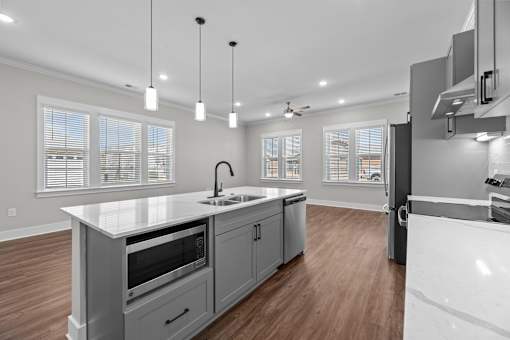 A modern kitchen with a white countertop and wooden flooring.