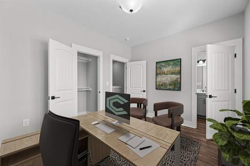A room with a desk, chair, and a painting on the wall.