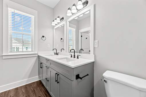 A bathroom with a white tub, a large mirror, and a window with blinds.